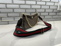 a gucci bag with a chain strap sitting on top of a sink