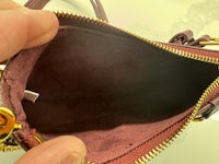 a person holding a burgundy purse with a zipper