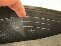 a person is holding a black purse with a zipper